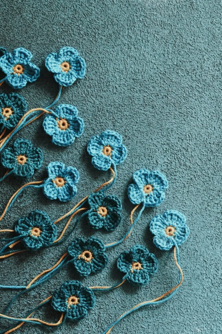 A cluster of small crocheted flowers arranged on a coloured surface