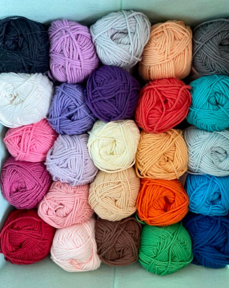 Pink, blue and yellow yarn balls used for small amigurumi projects