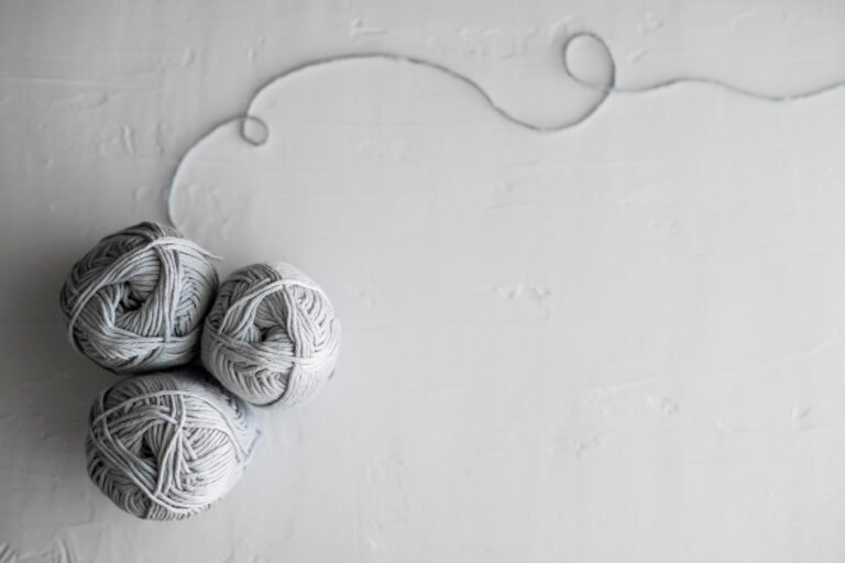 Three white cotton yarn balls photographed from above